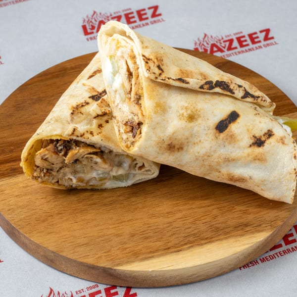 Two grilled chicken shawarma wraps with creamy sauce on a wooden board, against a branded background.