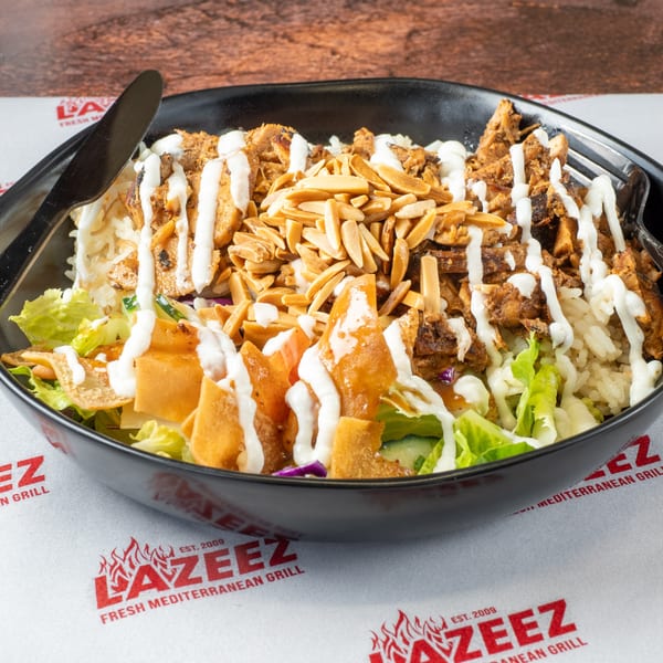 Lazeez Mediterranean bowl with chicken, rice, lettuce, fried pita, almonds, and white sauce.