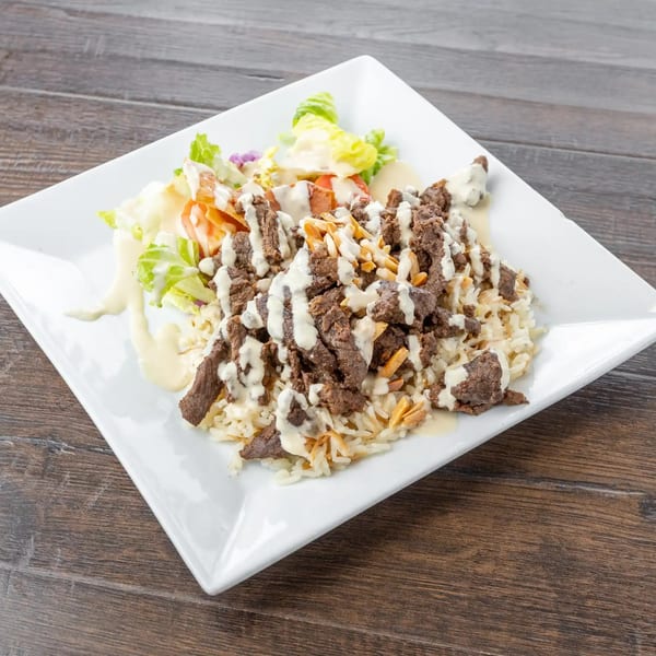 Lazeez Fresh Mediterranean Grill's rice plate with meat, almonds, and a side salad, drizzled with sauce.
