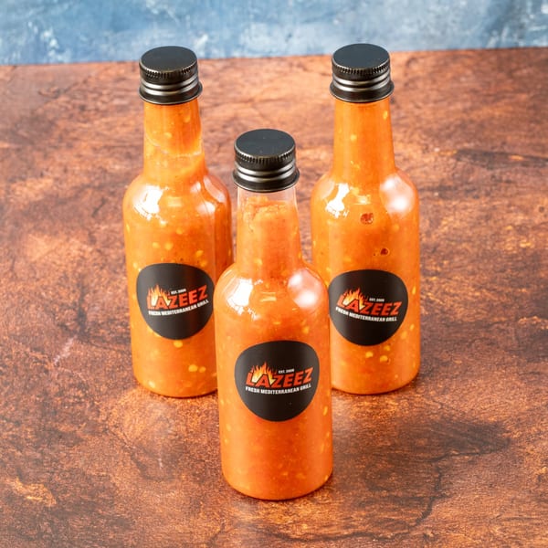 Three bottles of Lazeez Fresh Mediterranean Grill hot sauce with black labels.